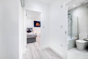 a white bathroom with a bed and a bath tub at Luxurious 1 Bed Serviced Apartment with Wi-Fi in Corby