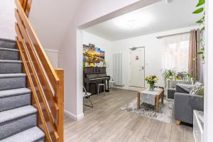 a living room with a staircase and a piano at Prestige Guest House Cambridge Modern Ensuite Rooms in Cambridge