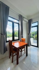 a dining room with a table and chairs and windows at Bao An Homestay Mai Chau in Mai Châu