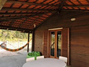 a room with a table and chairs and a hammock at Casa De Praia Galheta in Farol de Santa Marta