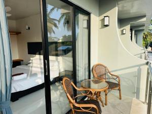 a balcony with a table and chairs and a bed at Rindhali Thoddoo in Thoddoo
