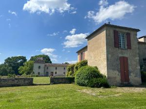 an old stone building with a red door in a yard at Beaulieu Saint Come in Saint-Côme