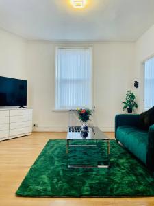 a living room with a couch and a green rug at Cozy Cottage in Liverpool