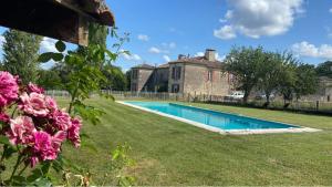 a swimming pool in front of a house with pink flowers at Beaulieu Saint Come in Saint-Côme