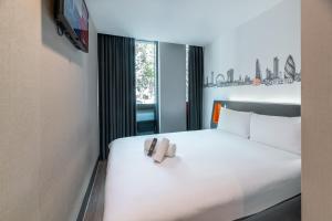 a bedroom with a white bed with two shoes on it at easyHotel London City Shoreditch in London