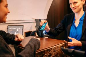 a woman is handing a credit card to a customer at Hotel Palais26 in Villach