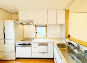 a kitchen with white cabinets and a sink at Yunokawa Onsen KOMOREBISO in Hakodate