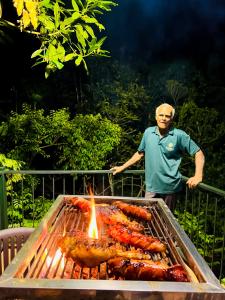 a man standing next to a grill with hot dogs at Niwana Resort in Ratnapura