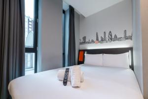 a bedroom with a white bed with two towels on it at easyHotel London City Shoreditch in London