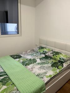 a bed with a green and white comforter and pillows at Mirror Apartments in Petrovec