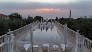 a pool of water with chairs and tables on a bridge at Villa Olivera Hotel in Tḩūm at Taḩtā