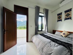 two beds in a room with a door and a window at Bao An Homestay Mai Chau in Mai Châu