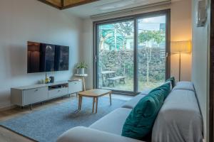 a living room with a couch and a tv at Joohane Jejudo House in Jeju