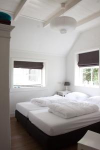 two beds in a white room with two windows at De Reggestee in Hellendoorn