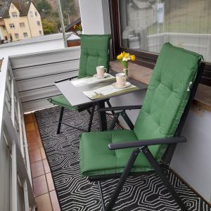 two green chairs and a table on a balcony at Ferienwohnung " Am Dorfbrunnen" in Dienethal