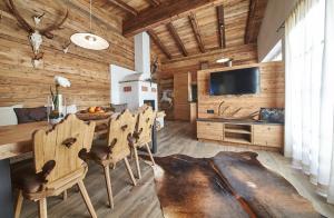 a dining room with a table and chairs and a television at Panorama Chalets by we rent, JOKERCARD INCLUDED in Saalbach-Hinterglemm