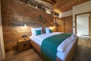 a bedroom with a large bed with wooden walls at Panorama Chalets by we rent, JOKERCARD INCLUDED in Saalbach-Hinterglemm