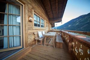 a wooden balcony with a table and chairs on it at Panorama Chalets by we rent, JOKERCARD INCLUDED in Saalbach-Hinterglemm