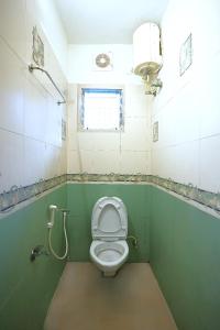 a bathroom with a toilet with green walls and a window at Blessings select DLF in Chennai