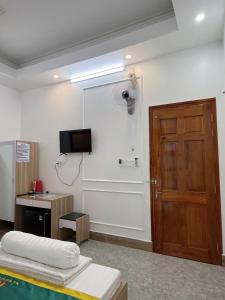 a room with a door and a tv on the wall at NHÀ NGHỈ LÊ ĐƯỢC 2 in Hà Tiên