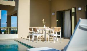 a dining room with a table and chairs next to a pool at Villa Artemis 4 - Etheras Properties in Kythira