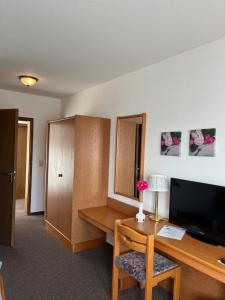a room with a desk with a computer and a television at Hotel Landhaus Adensen in Nordstemmen