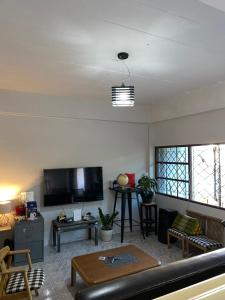 a living room with a couch and a flat screen tv at Only fan guesthouse in Chumphon