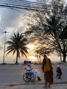 a monk pushing a child in a cart on a street at Only fan guesthouse in Chumphon +9 photos