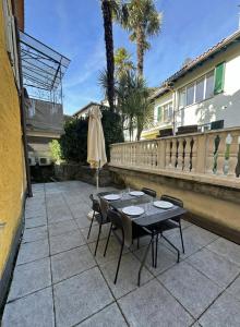 a patio with a table and chairs and an umbrella at Gemütliche Wohnung im Borgo Ascona in Ascona