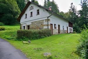 a white house with a grass yard next to a road at Chalupa U Kapličky Pastviny in Pastviny