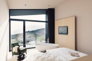 a bedroom with a bath tub and a large window at Hotel Milla Montis in Maranza