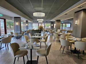 a dining room with tables and chairs and windows at Hotel Három Gúnár in Kecskemét