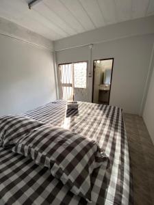 a bed in a room with a checkered blanket at Only fan guesthouse in Chumphon