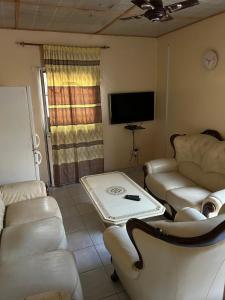 a living room with couches and a table and a tv at Room 01 in Serekunda