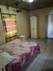 a bedroom with a large bed with a purple blanket at Room 01 in Serekunda