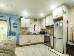 a kitchen with white cabinets and a refrigerator at Swallows Rest Cottage KZN in Scottburgh
