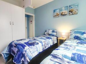 two beds in a room with blue and white at Swallows Rest Cottage KZN in Scottburgh +16 photos
