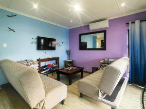 a living room with two chairs and a tv at Swallows Rest Cottage KZN in Scottburgh