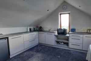 a large kitchen with white cabinets and a window at Studio Sleeps 2 -Private Hot Tub -Enclosed Garden in Killarney