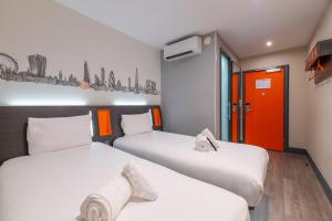 two beds in a room with an orange door at easyHotel London City Shoreditch in London