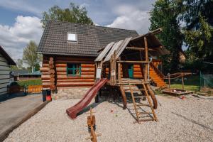 a log cabin with a slide and a playground at Penzion Rak Wellness in Černá v Pošumaví