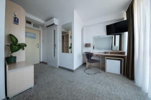 a room with a desk with a computer and a tv at Hotel Logos in Warsaw
