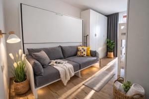a living room with a gray couch and a large screen at Bormio7 con parcheggio, pista ciclabile, vicino piste sci e terme in Valdisotto
