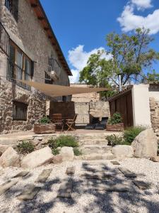 a stone house with a patio and a tree at Mas Lloretó - El Rossinyol in Copóns +17 photos