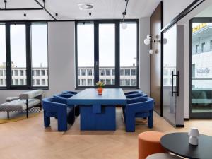 a blue table and chairs in a room with windows at smartments Bielefeld Hauptbahnhof in Bielefeld