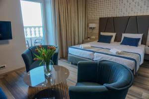 a hotel room with a bed and two chairs and a table at Hotel Fiesa in Piran