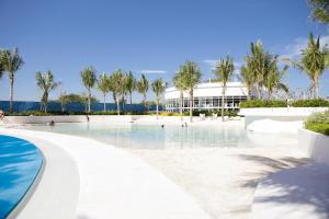 a resort swimming pool with palm trees and a building at Kaiah's Haven at Azure North San Fernando Pampanga in San Fernando