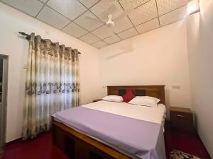 a bedroom with a bed with white sheets and red pillows at Dan Sewana in Nochchiyagama