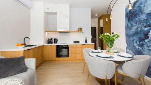 a living room with a table and chairs and a kitchen at Sol Marina 231 in Wiślinka +8 photos