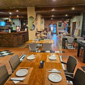 a dining room with wooden tables and chairs at Forest Gate Cabins in Plettenberg Bay